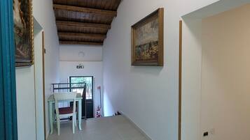 Un pasillo con techo de madera, un comedor con mesa y sillas, y un cuadro en la pared.