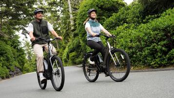 Two people riding bicycles on a road surrounded by greenery.