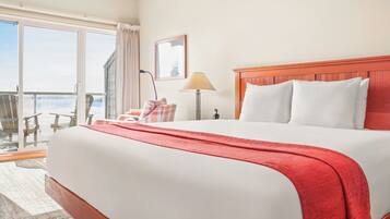 Une chambre d’hôtel avec un grand lit, un balcon avec vue, un bureau et une chaise.