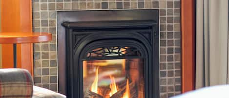 Una chimenea con detalles de azulejos, un sillón a cuadros y una mesa de madera.