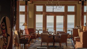 A spacious room with large windows, a chandelier, and a surfboard on the wall. - Long Beach Lodge Resort (Tofino)