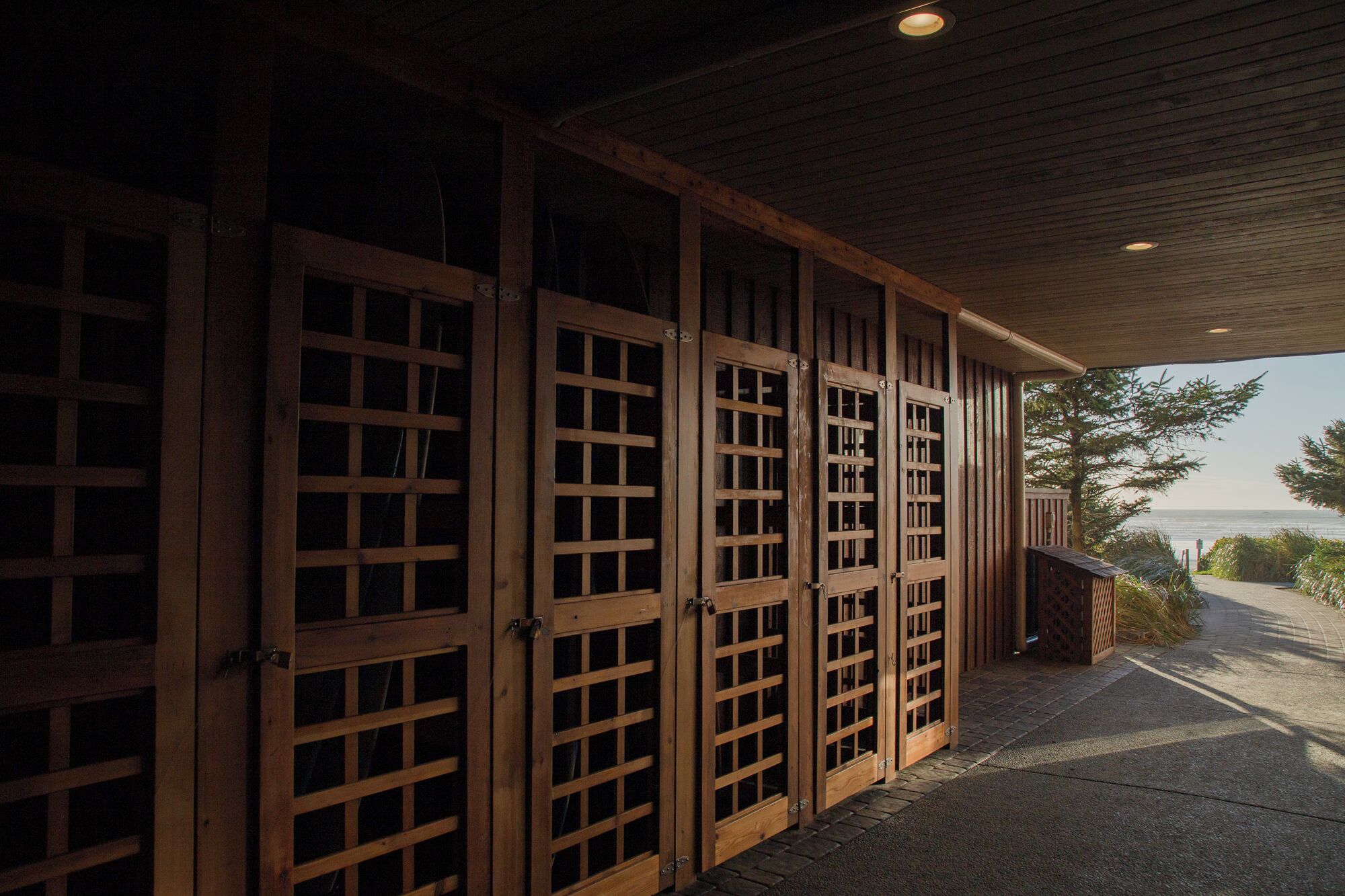 A covered outdoor area with wooden doors and a view of the sea.