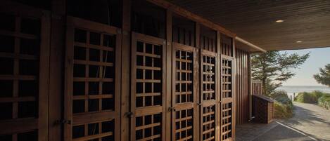 A covered outdoor area with wooden doors and a view of the sea.