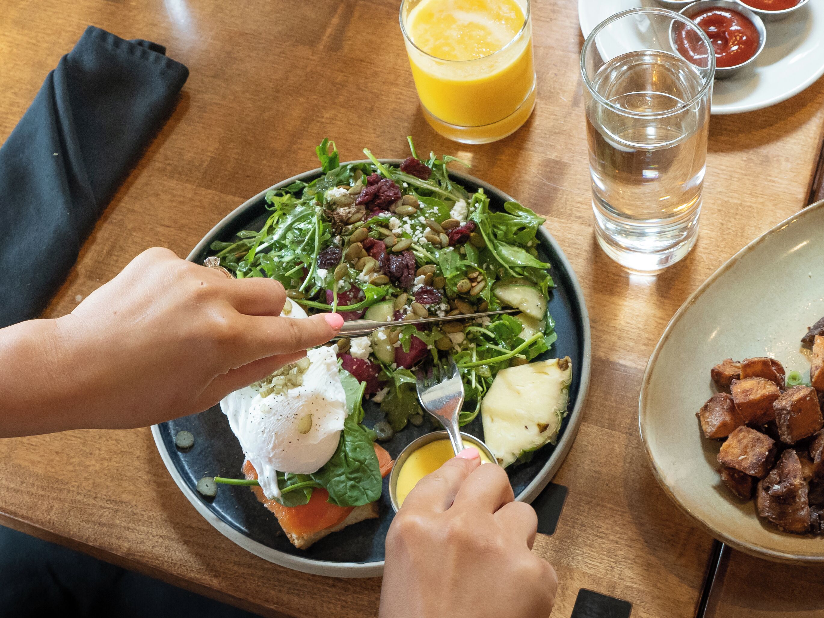 A dining table with a plate of food, a glass of orange juice, and a glass of water.