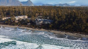 A coastal town with buildings near the beach and forested hills in the background. - Long Beach Lodge Resort (Tofino)