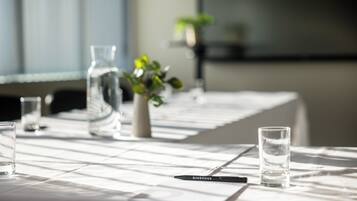 A conference table with water glasses, a pen, and a vase with a plant.