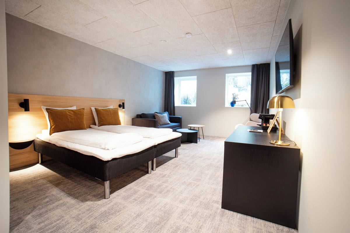 Une chambre d’hôtel moderne avec un grand lit, un bureau, un canapé et une petite table.
