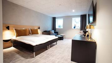 Una habitació d'hotel moderna amb un llit gran, un escriptori, un sofà i una taula petita.