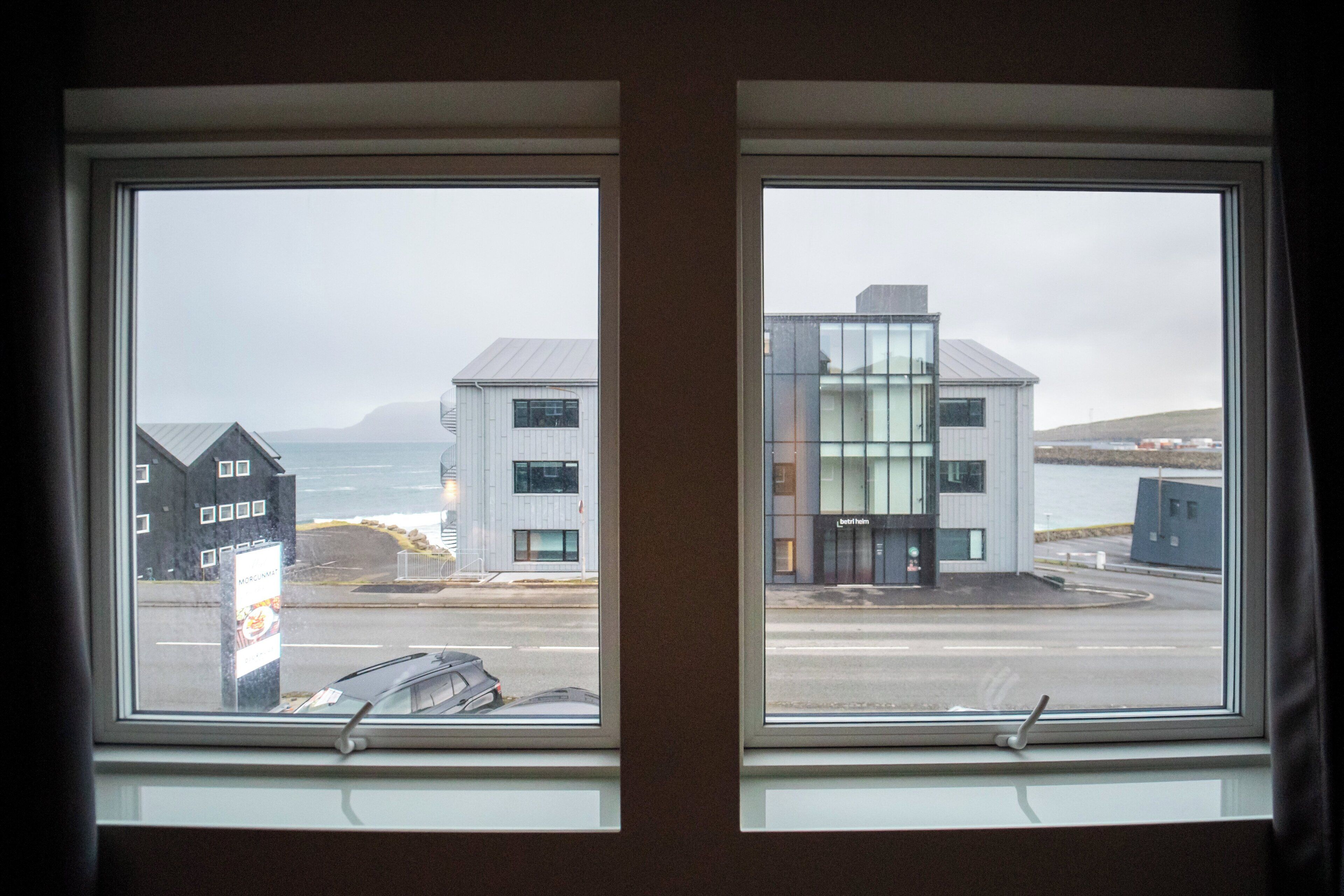Two windows with a view of buildings and a road.