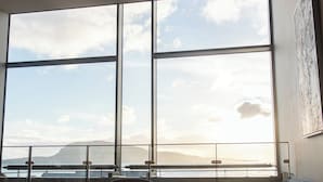 A modern room with large windows, a round table, two chairs, and a sofa. - Hotel Djurhuus (Tórshavn)