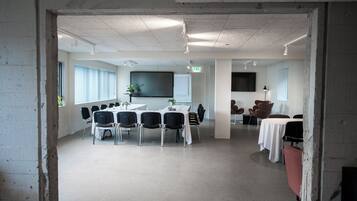Un salón de conferencias con una gran mesa, sillas y una pantalla para proyector.