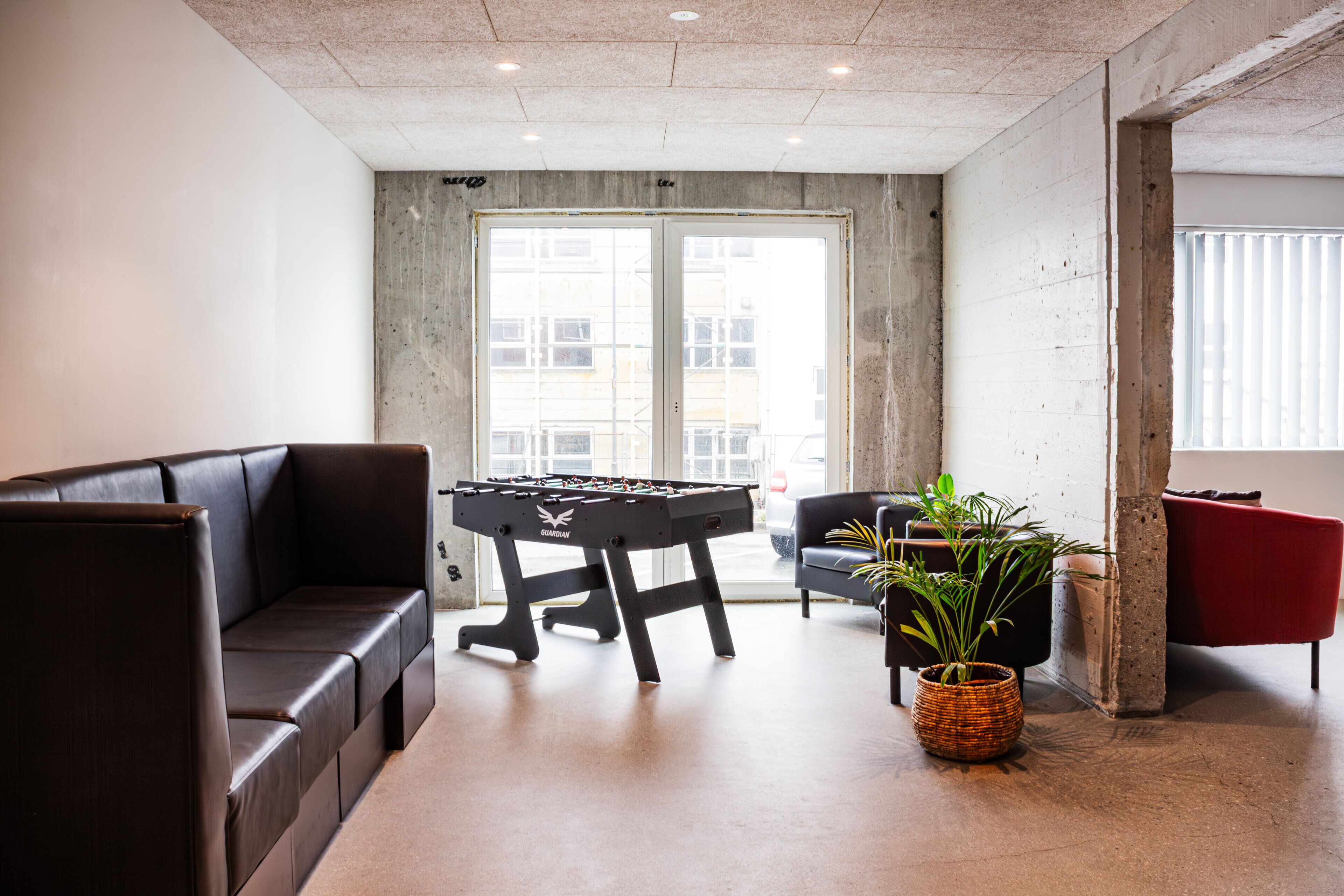 A modern room with a foosball table, a sofa, and a potted plant.