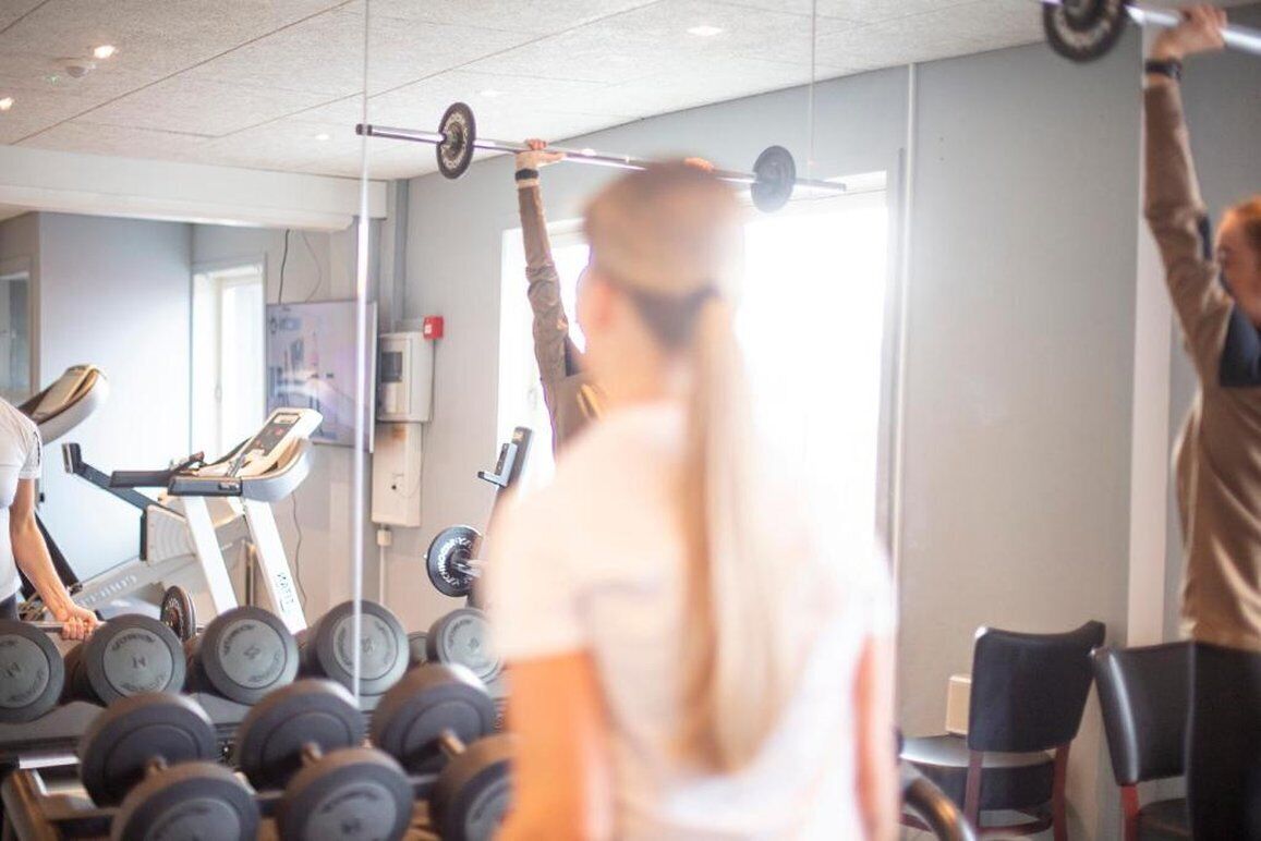 A gym with treadmills, dumbbells, and a barbell.
