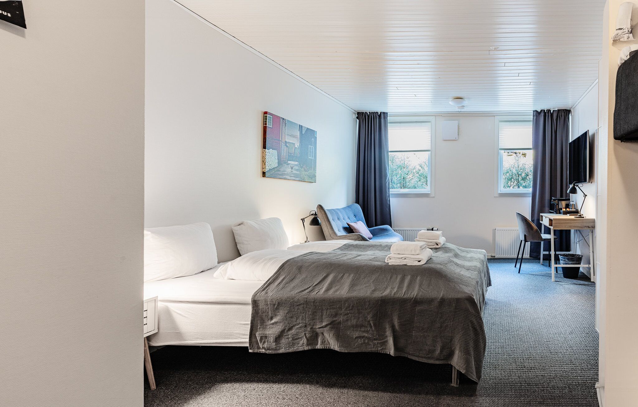 Une chambre d’hôtel avec un lit, un bureau, une chaise et un tableau au mur.