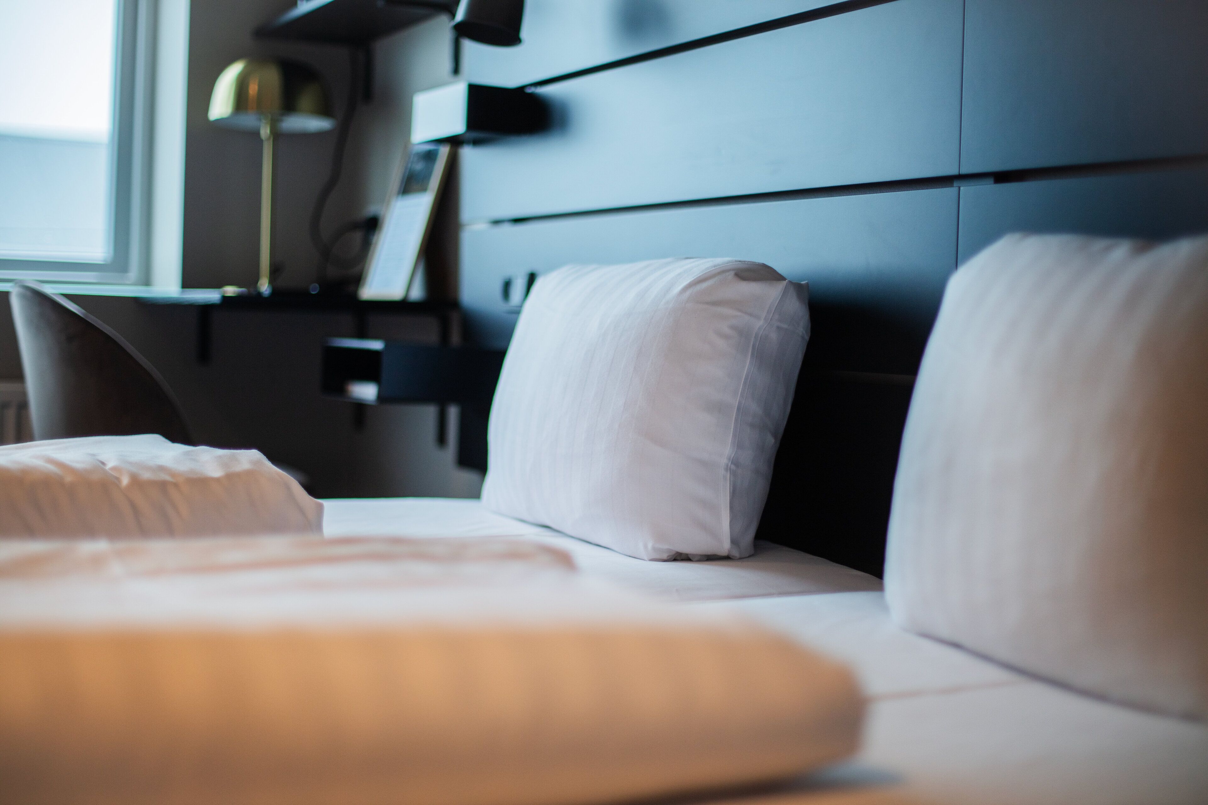 A neatly made bed with white linens in a hotel room.