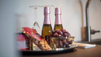 Una bandeja con dos botellas de vino, una copa, un bol de uvas y un paquete de aperitivos sobre una mesa.