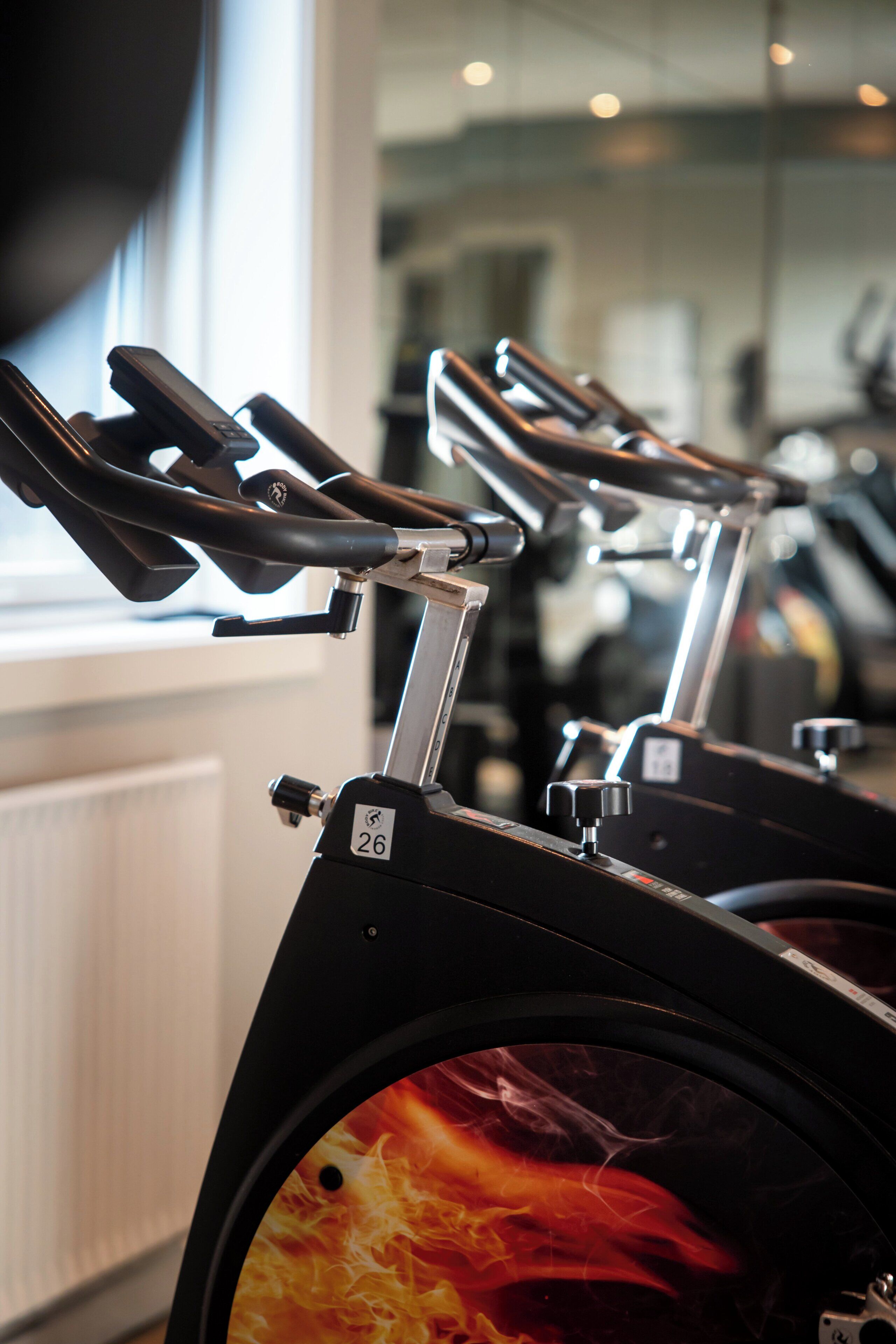 A stationary bike with a number 26 label, part of a gym with exercise equipment.