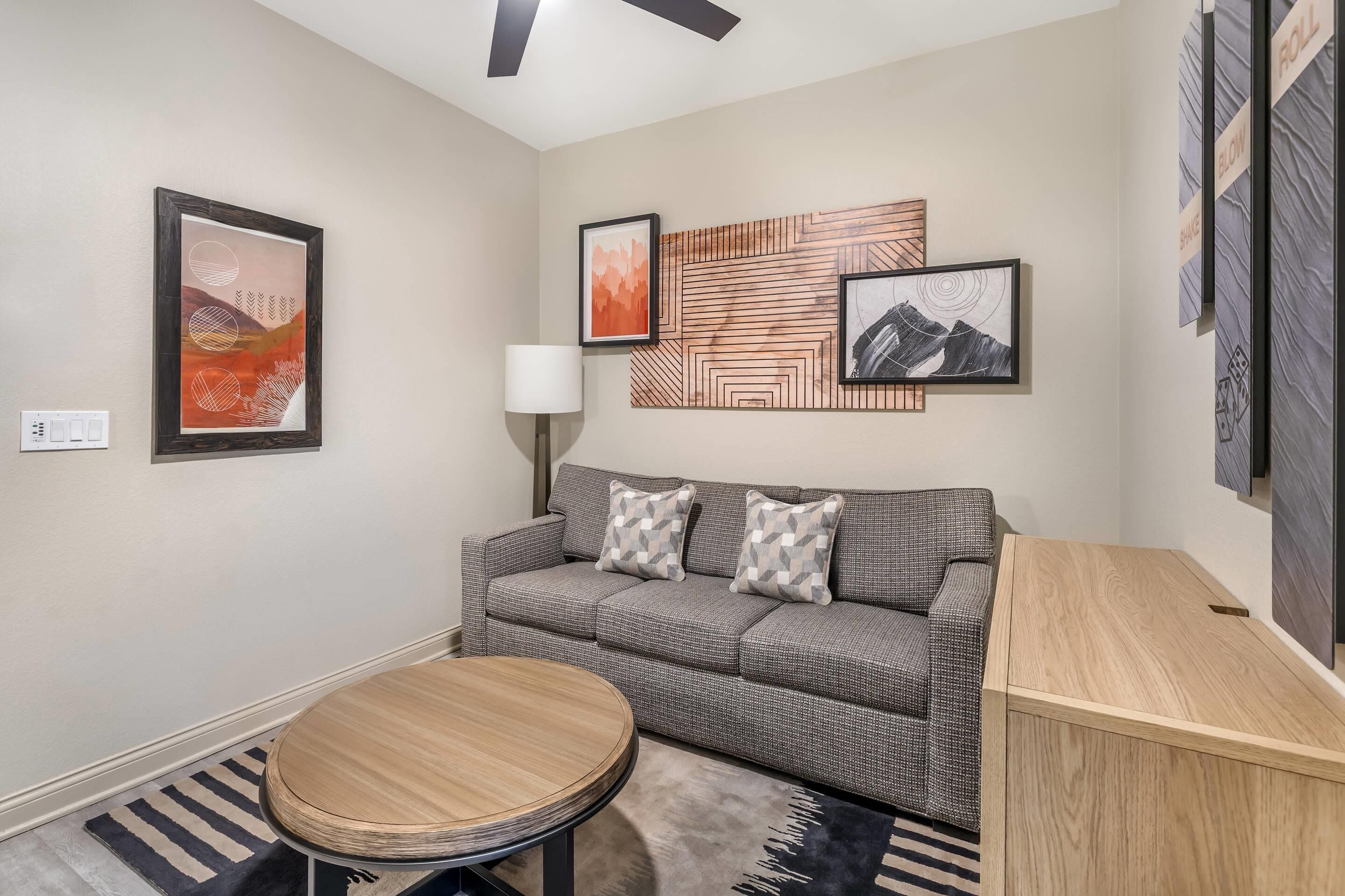 A modern living room with a sofa, round coffee table, and wall art.