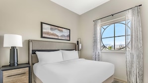 A hotel room with a bed, a nightstand with a lamp, a framed picture on the wall, and a window with curtains. - Bluegreen Vacations Club 36, an Ascend Collection Resort (Las Vegas)