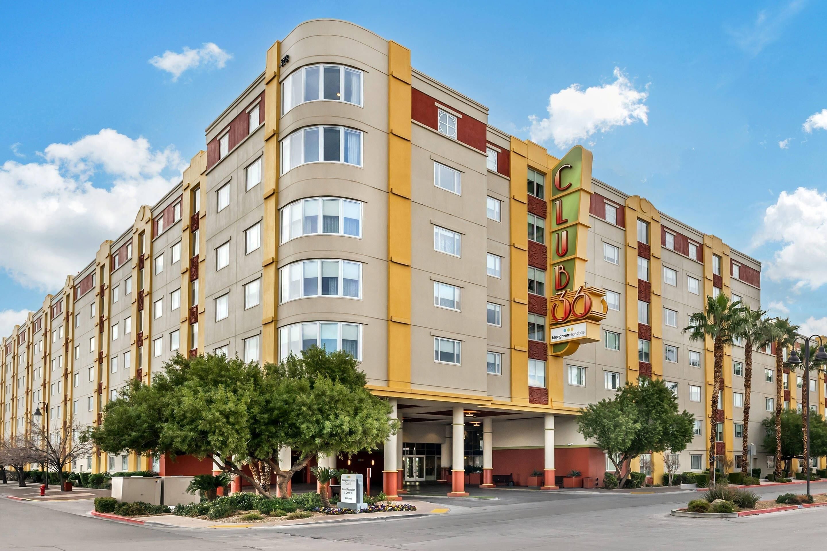 A multi-story hotel with a curved facade, a prominent 'Club' sign, and a landscaped entrance area.