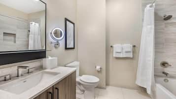 A modern bathroom with a large mirror, a sink, a toilet, and a shower area.