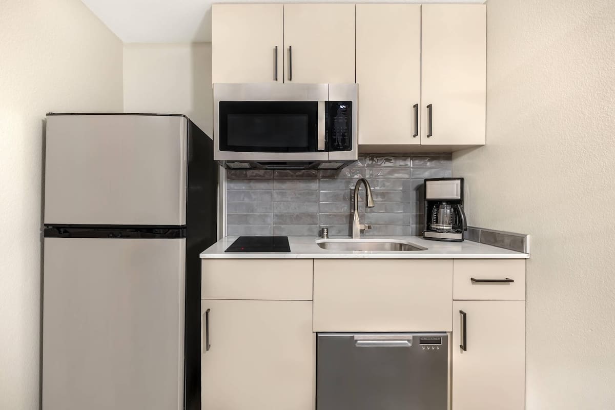 Una cocina compacta equipada con refrigerador, microondas, cafetera y lavavajillas.