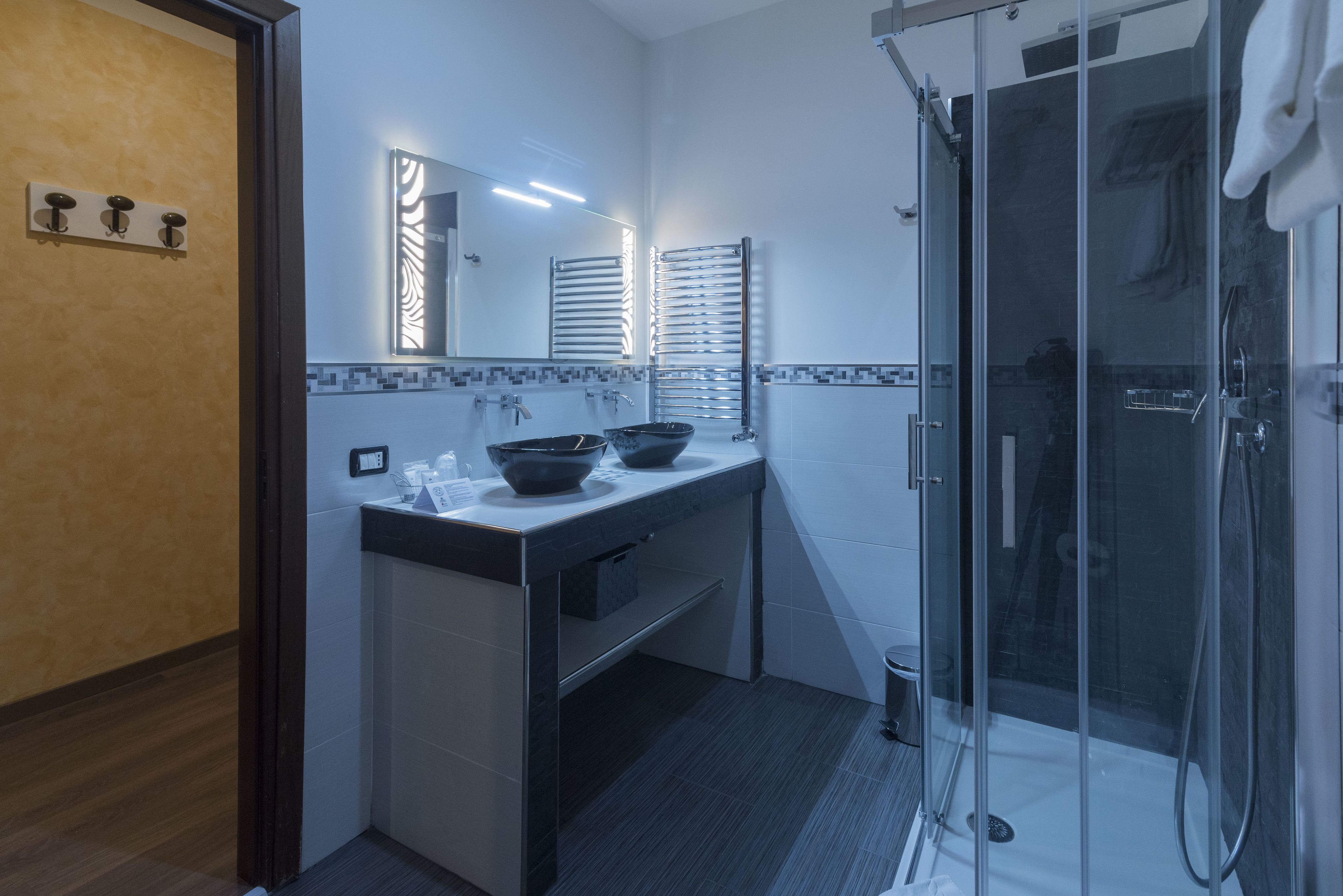 Un baño moderno con cabina de ducha de vidrio, tocador doble y un espejo grande.