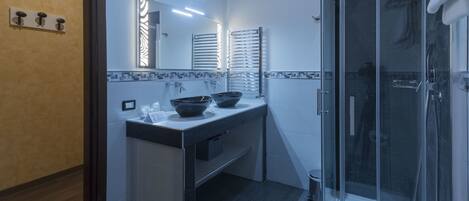 Un baño moderno con cabina de ducha de vidrio, tocador doble y un espejo grande.