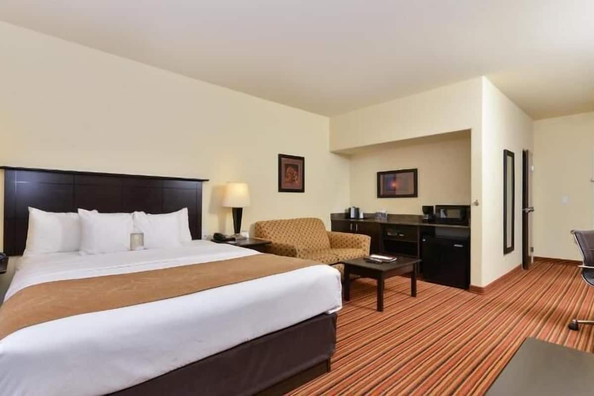 Une chambre d’hôtel équipée d’un lit, d’un bureau, d’une chaise, d’une machine à café et d’un four à micro-ondes.