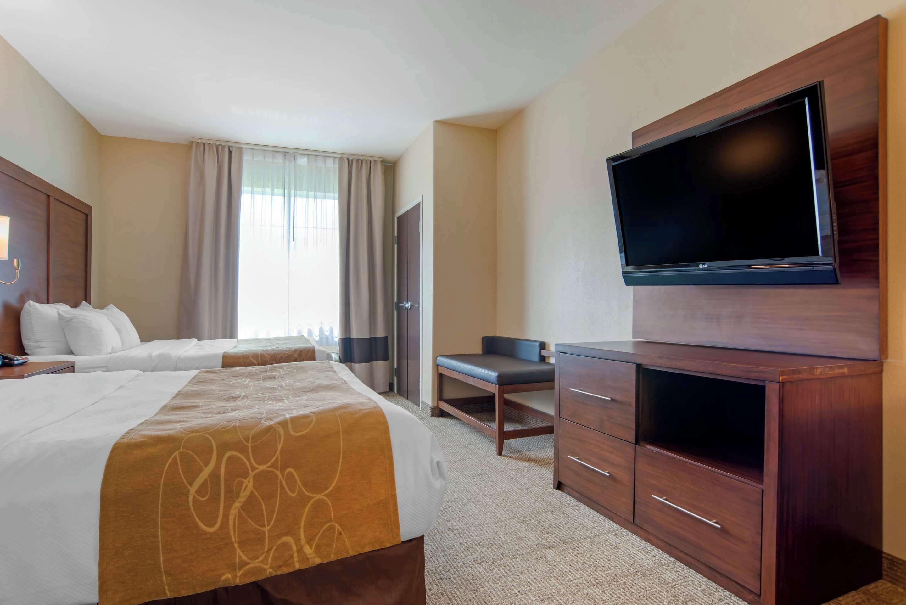 Habitación de hotel con dos camas, un televisor de pantalla plana, un escritorio y un armario.