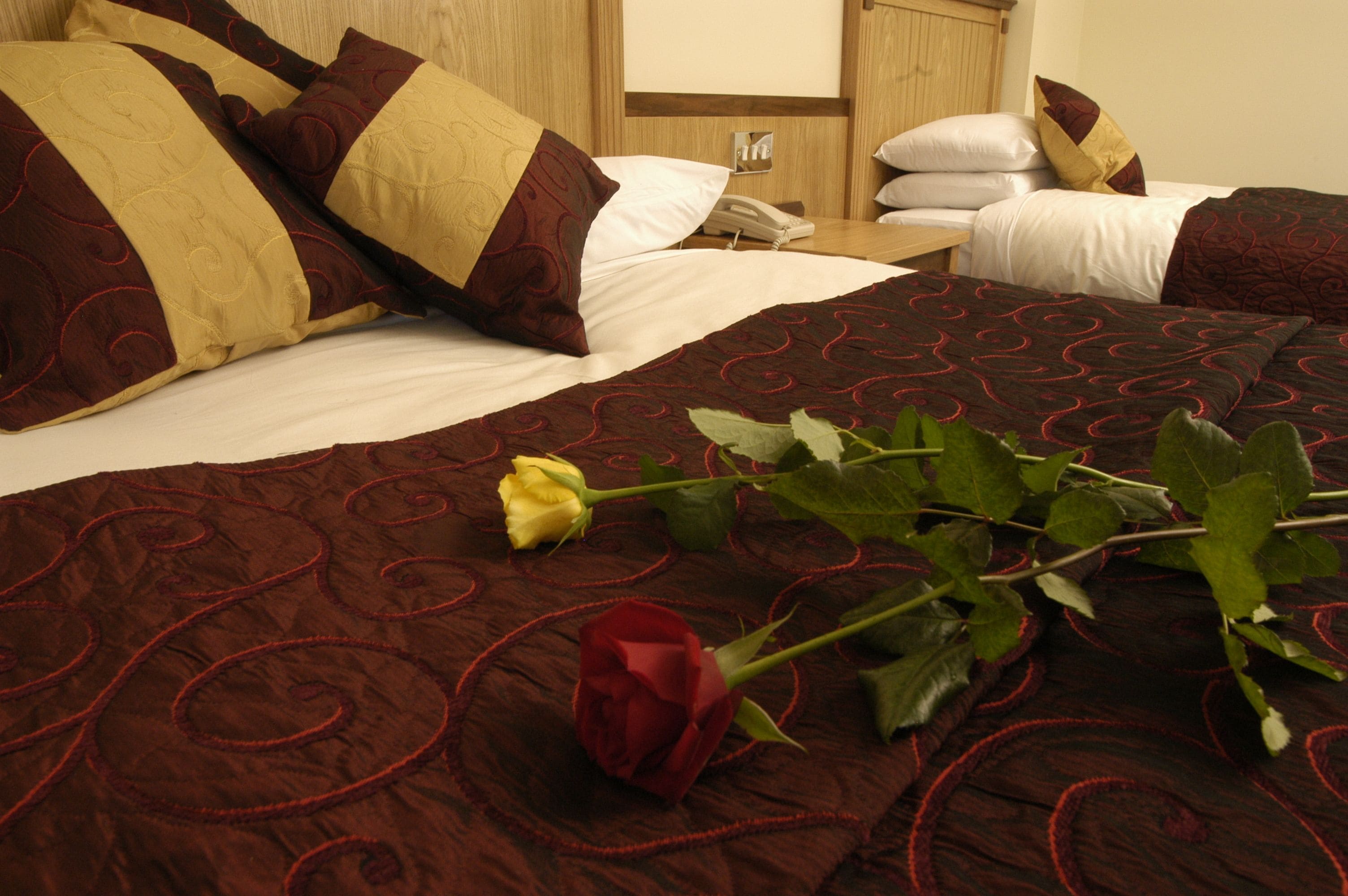 Habitació d'hotel amb un llit gran, vàries almoines, un telèfon al costat del llit i un ram de flors.