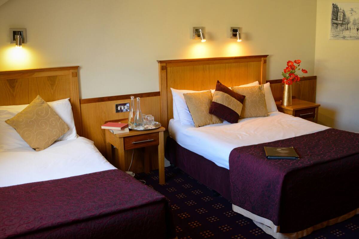 Two double beds with headboards, bedside tables, and lamps.