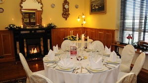 Un comedor formal con chimenea, elegantes manteles y una decoración clásica.