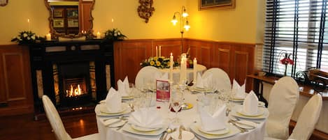 A formal dining room with a fireplace, elegant table settings, and classic decor.