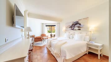 Habitación de hotel con cama, escritorio, silla, televisor y un cuadro en la pared.