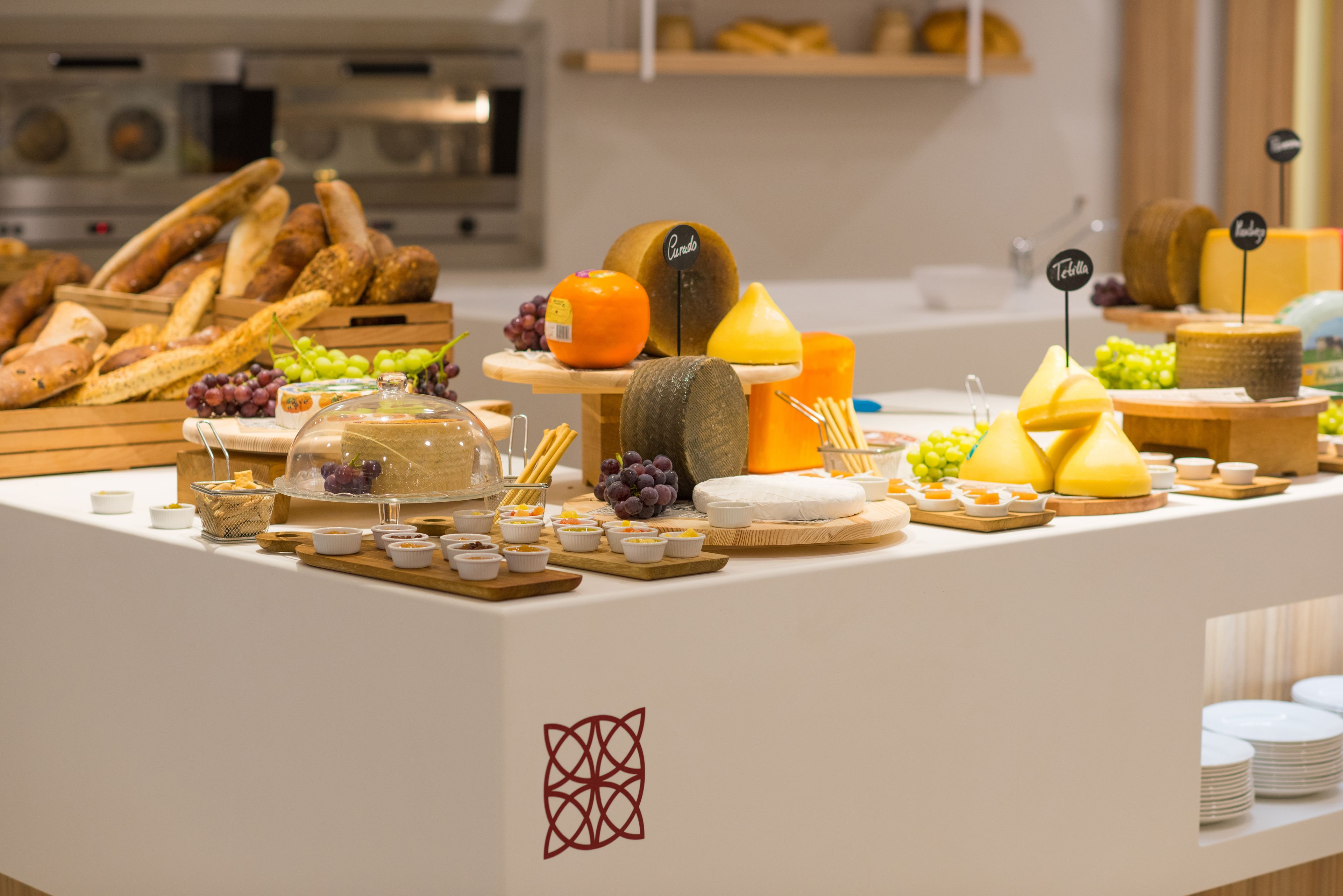 A buffet with various cheeses, fruits, and breads.