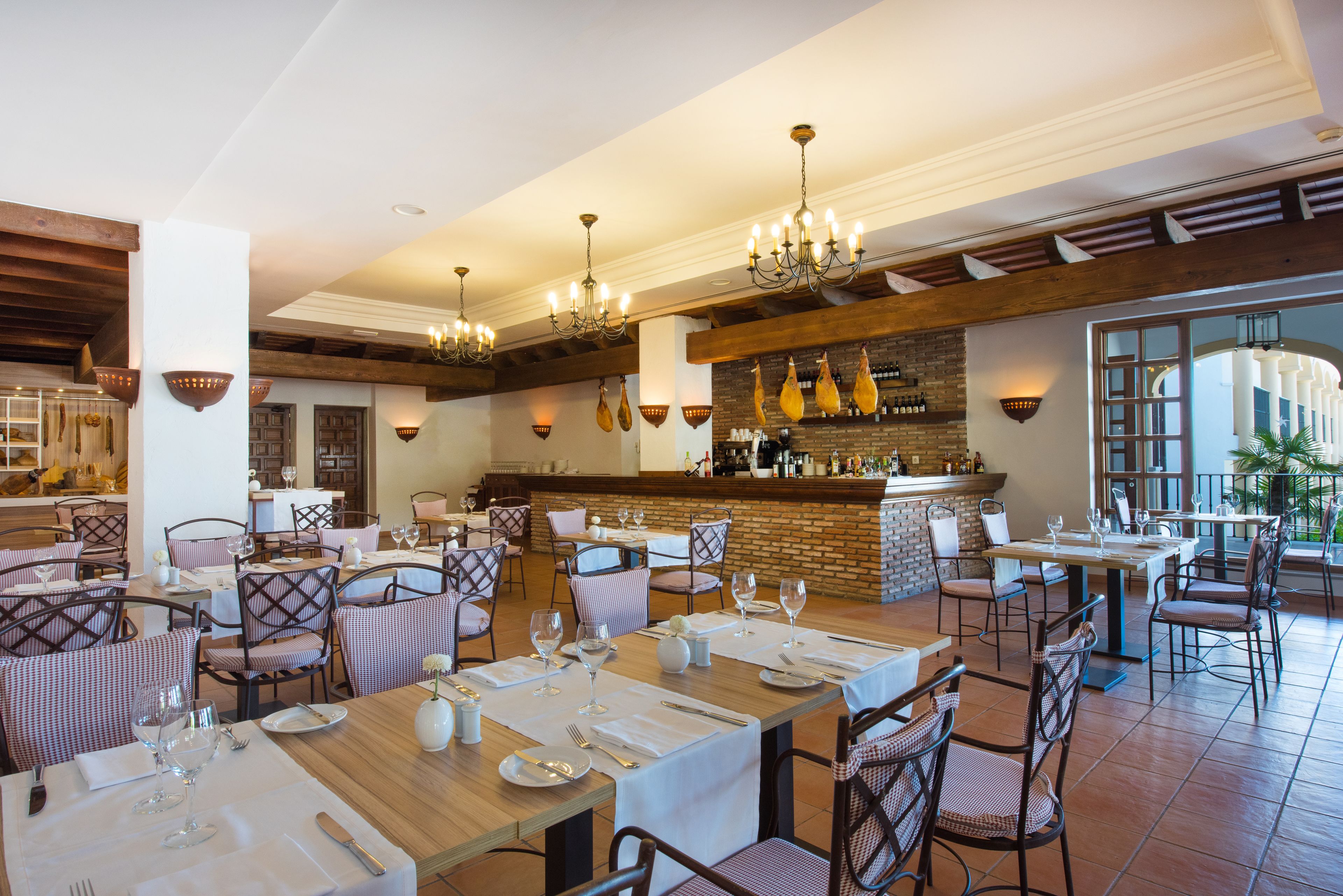 En restaurant med træborde og stole, en murstensvæg og hængende lysarmaturer.