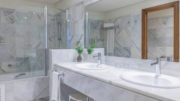 A modern bathroom with two sinks, a glass shower enclosure, and a large mirror.