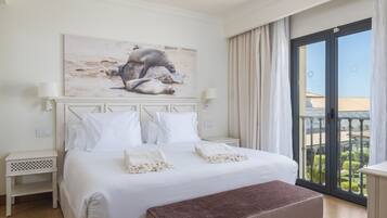 A hotel room with a large bed, a painting above the bed, a balcony with curtains, and a view of the outside.