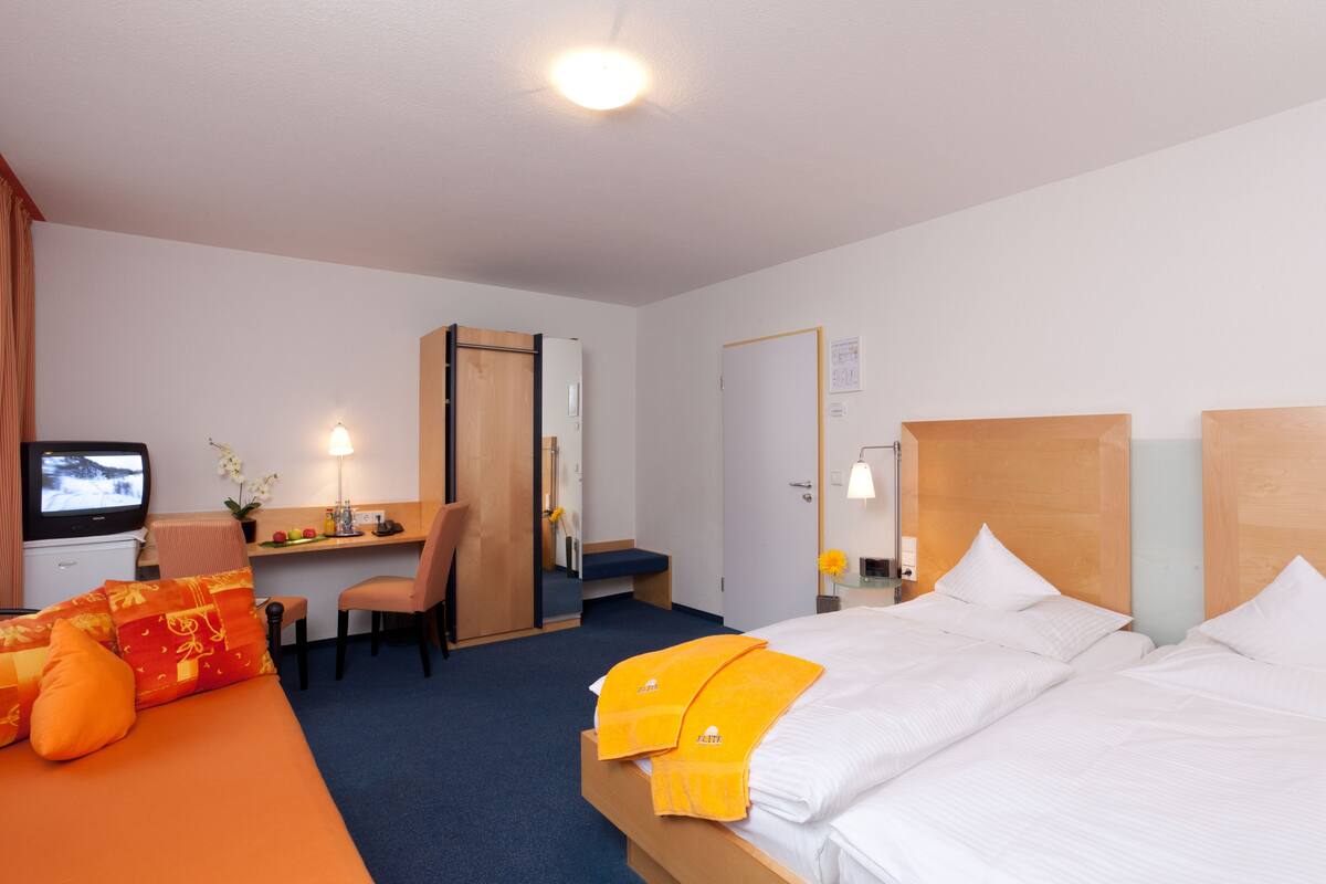 Une chambre d’hôtel avec un lit, un bureau, une télévision et une chaise.