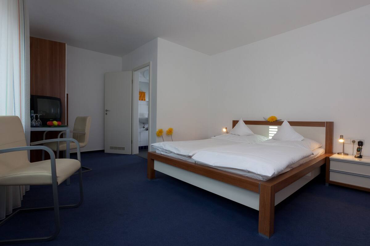 Une chambre d’hôtel comprenant un lit, un bureau avec une chaise, une télévision et une table de chevet avec une lampe.