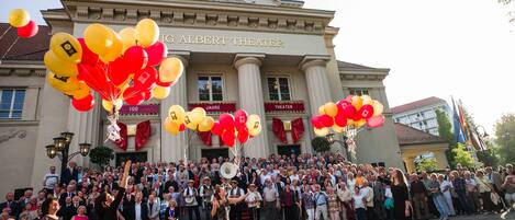 Una multitud frente a un edificio con columnas y un cartel que dice 'Albert Theater'.