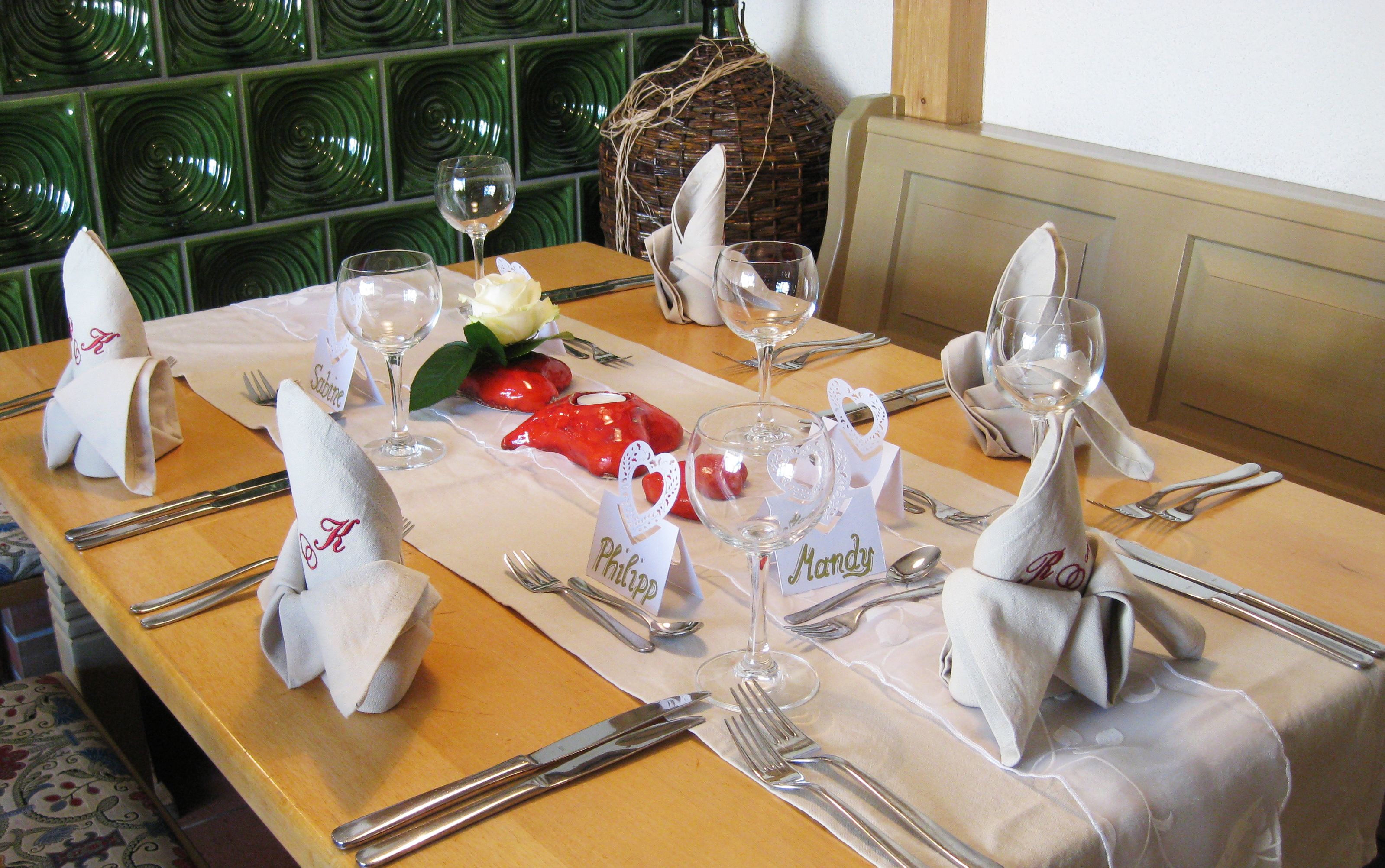 A dining table set with white napkins, silverware, and glassware, with name cards and a decorative centerpiece.