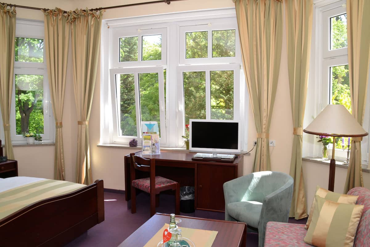 A hotel room with a bed, desk, chair, and a television.