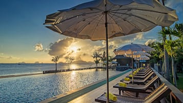 Una piscina al aire libre, sombrillas, sillones reclinables de piscina