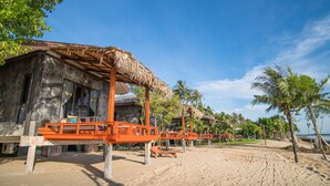 A beachside resort with thatched-roof huts, wooden deck chairs, and palm trees. - Islanda Hideaway Resort (Krabi)