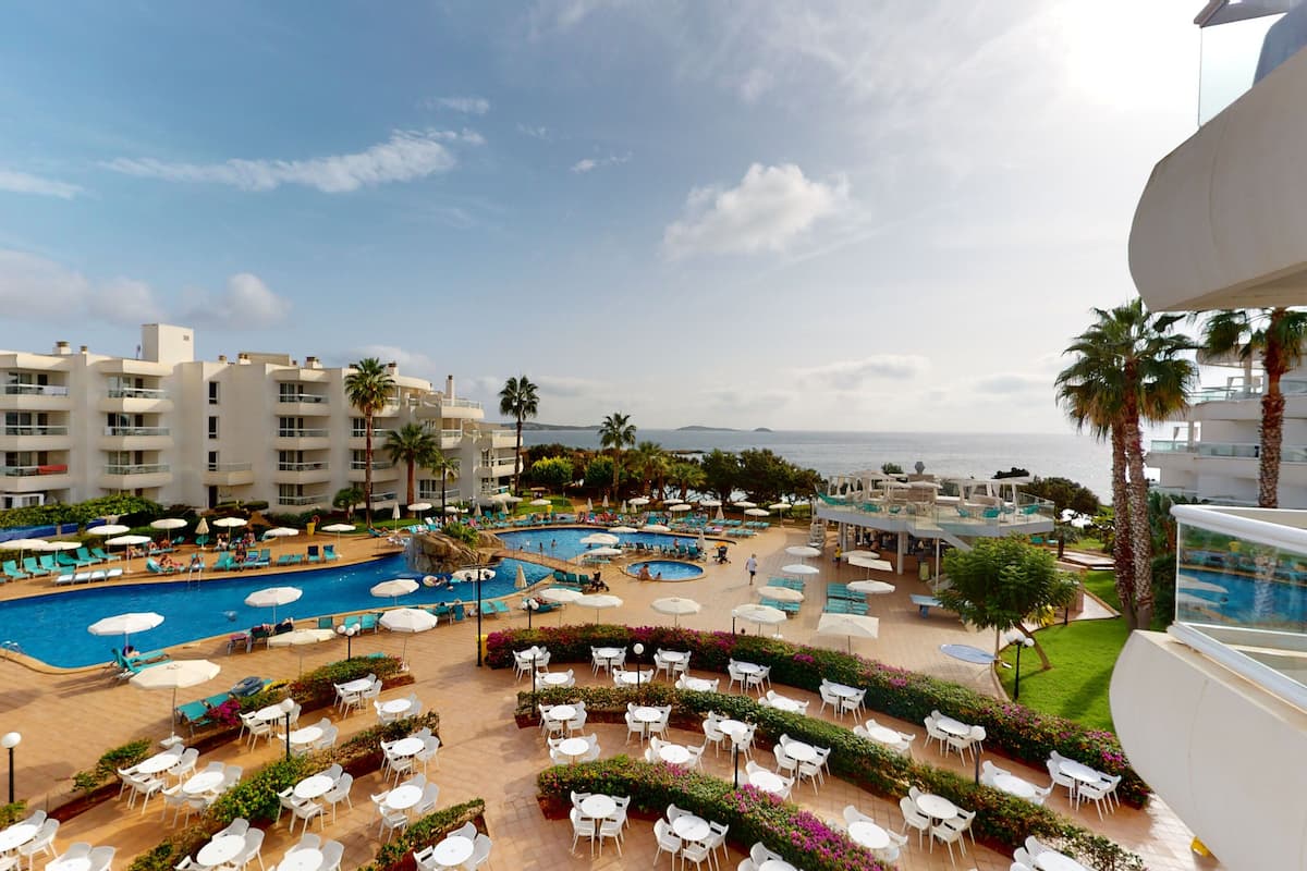 Un resort con múltiples piscinas, zonas de estar al aire libre y vistas al mar.