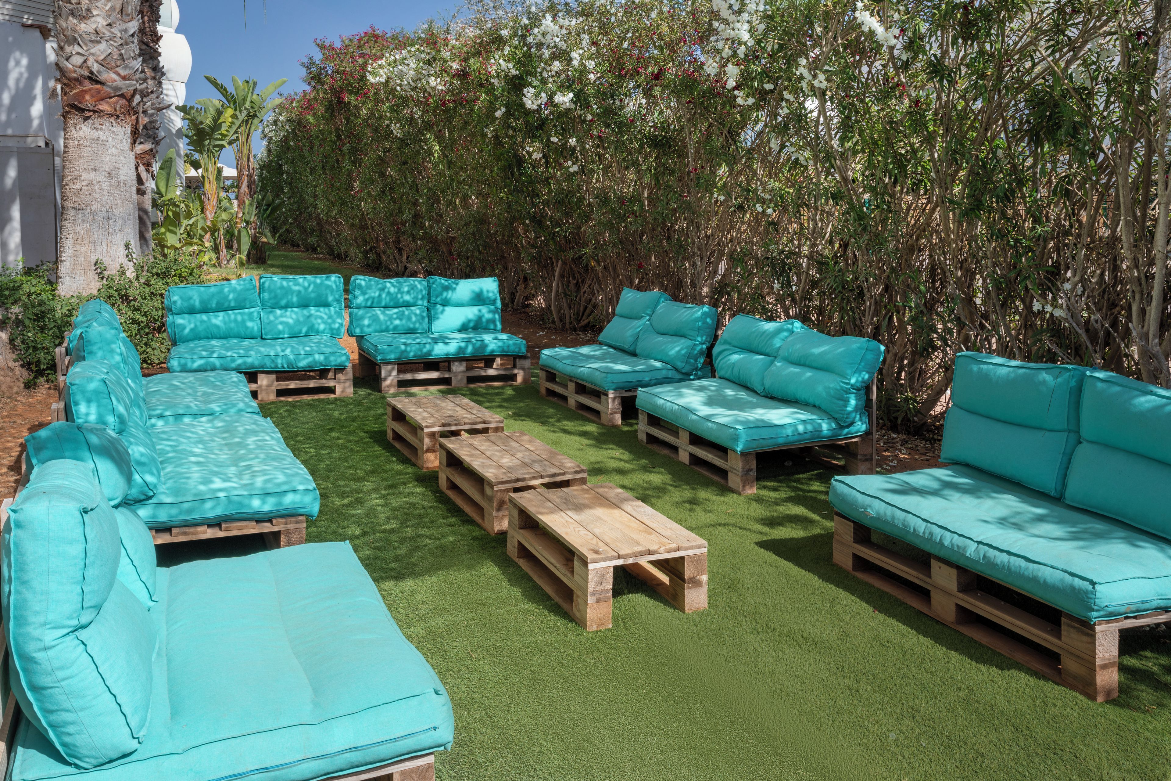 Un espace patio doté de différents types de sièges, notamment des canapés et des bancs, et entouré d’une végétation luxuriante.
