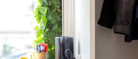 A window sill with a plant, a kettle, and fruits.