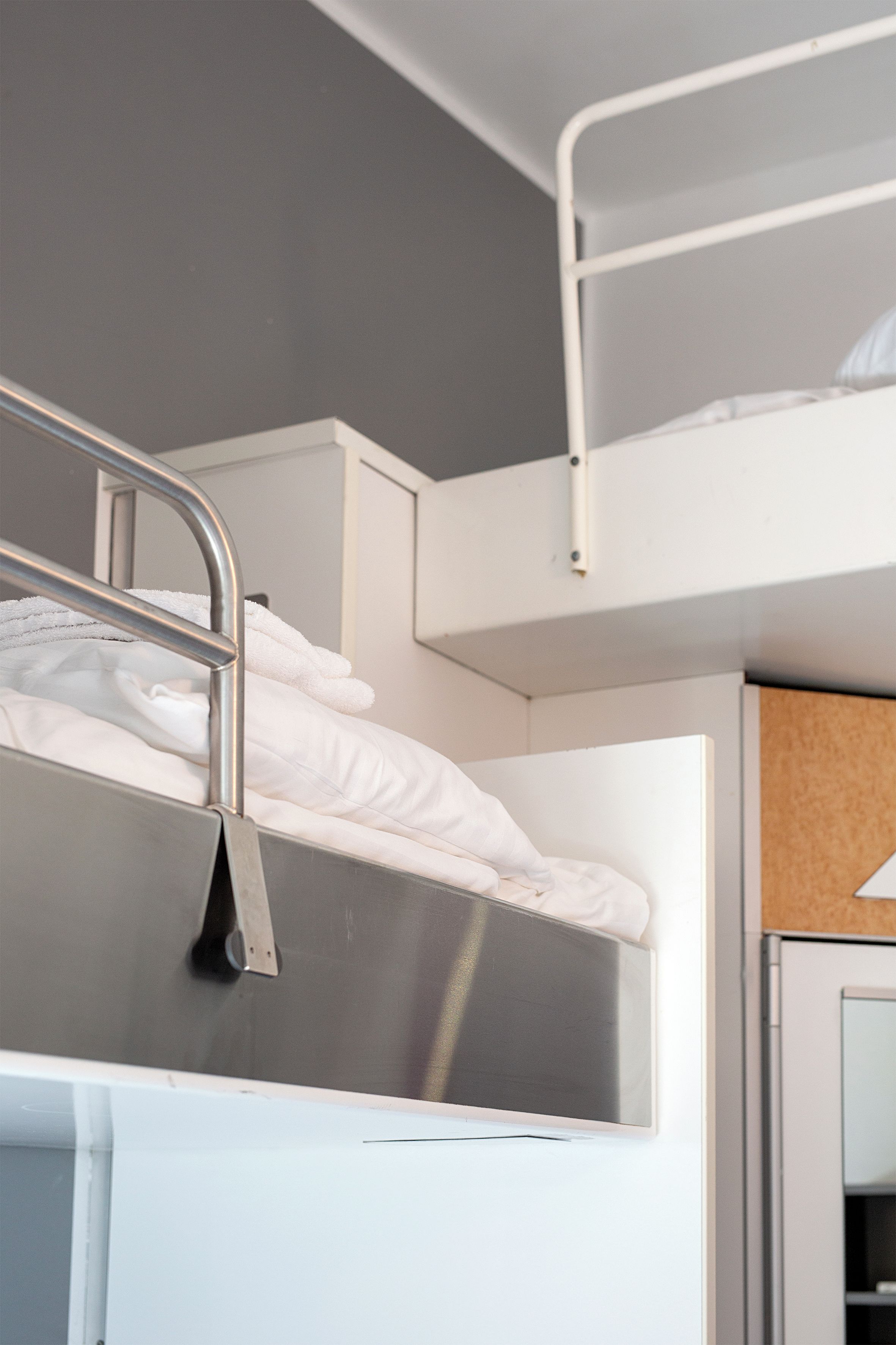 Una cama litera con barandillas metálicas y un colchón blanco.